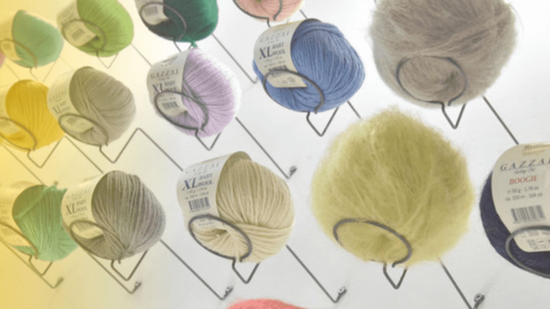 Bunte Wollknäuel in verschiedenen Farben, ordentlich auf Regalen präsentiert, repräsentieren die Vielfalt der Handarbeitsmaterialien bei der h+h Cologne.